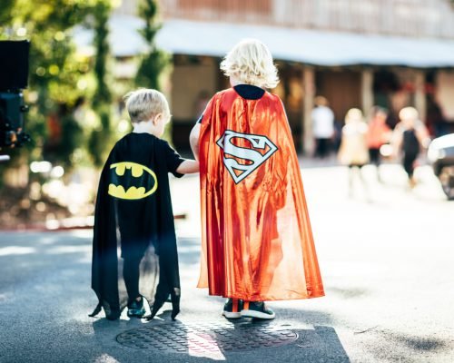 two-boys-holding-hands-wearing-superman-capes-at-movie-world